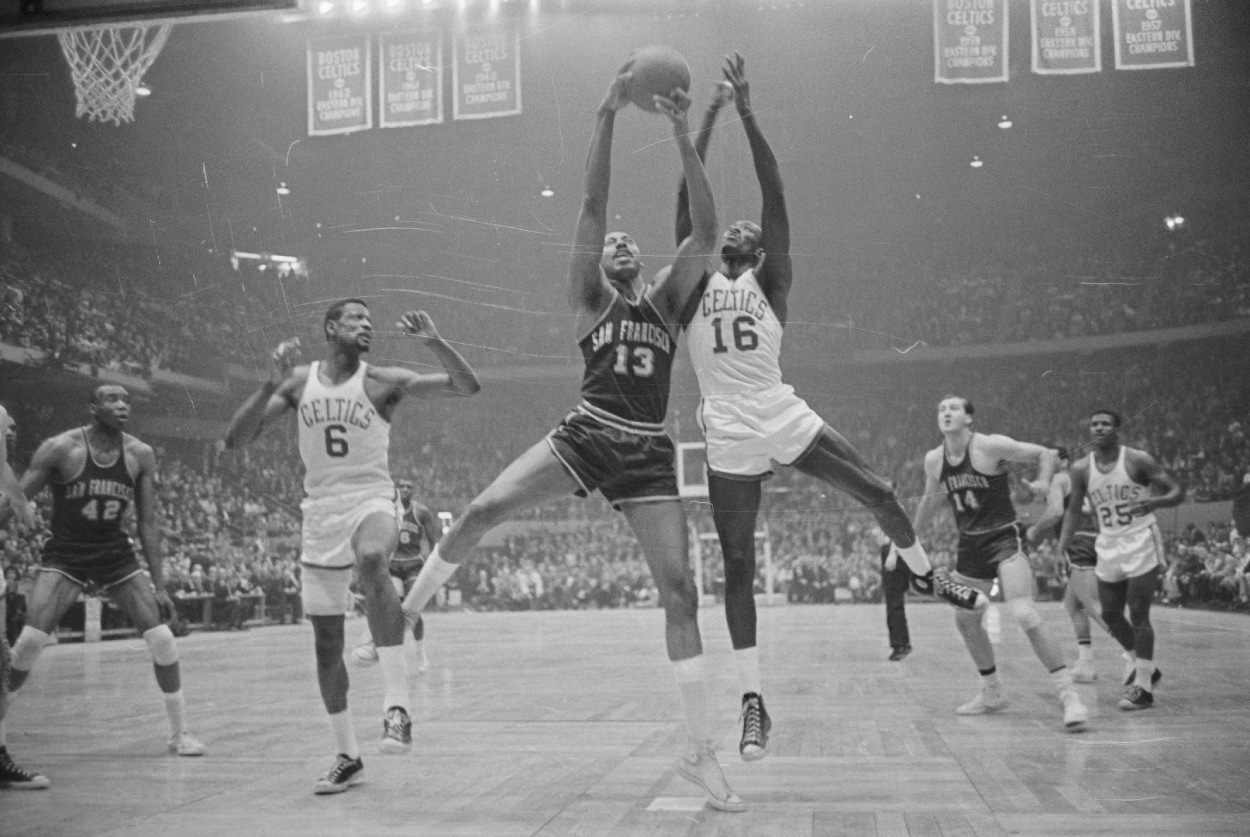 Wilt Chamberlain (13) of the Warriors' fights for rebound with (16) Tom Sanders of the Celtics as Bill Russell (6) looks on.