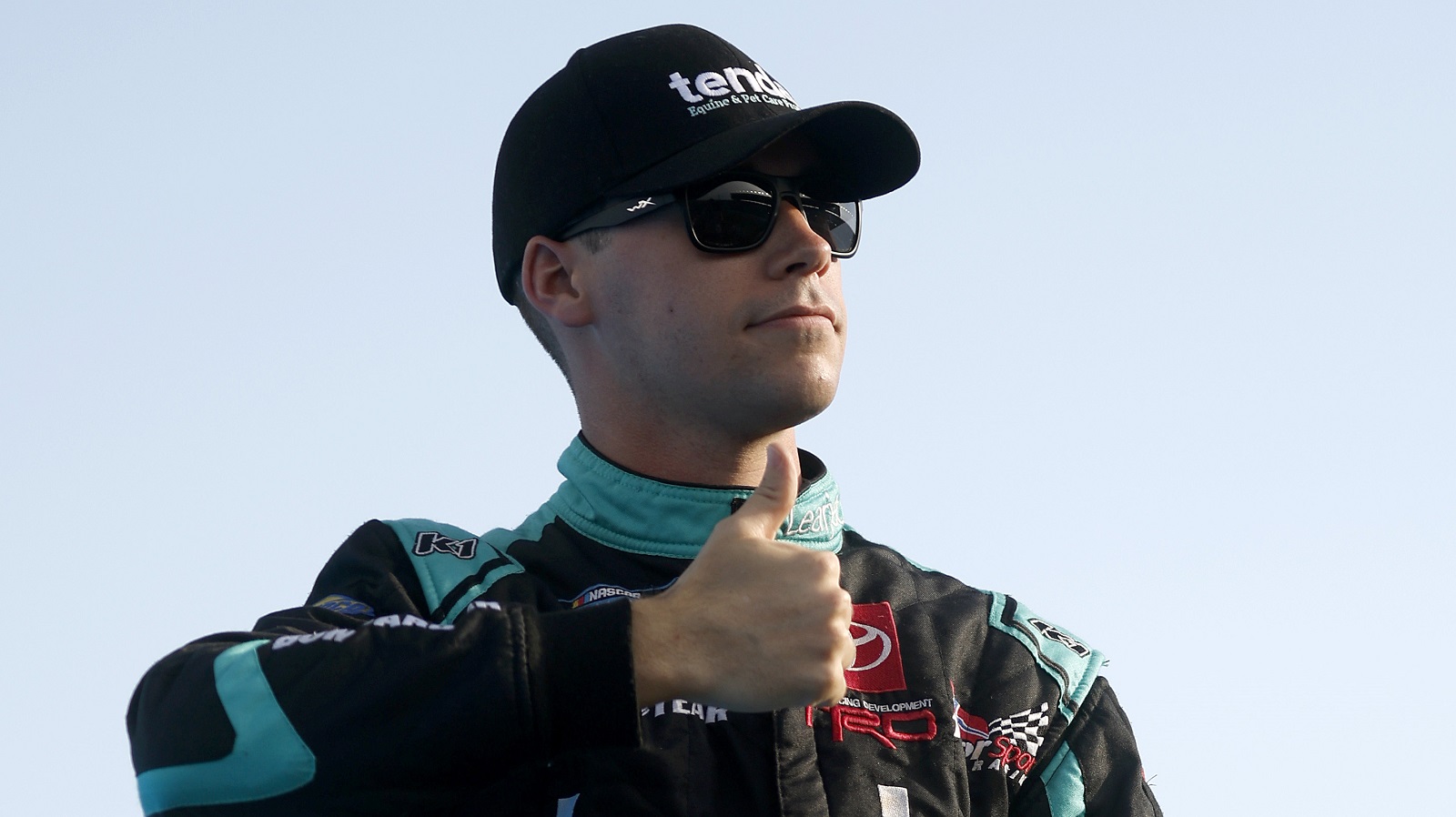 Ben Rhodes, driver of the No. 99 Toyota, gives a thumbs-up to fans as he walks onstage during driver intros prior to the NASCAR Camping World Truck Series Heart of America 200 at Kansas Speedway on May 14, 2022.