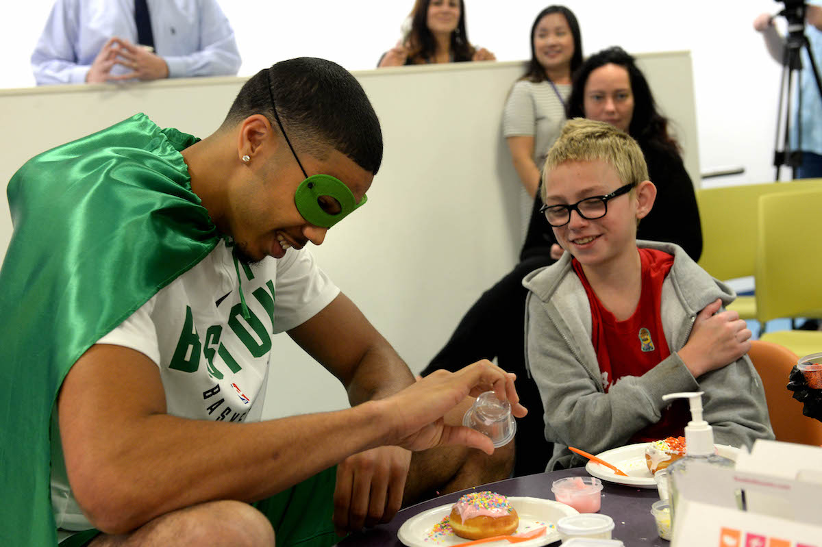 Boston Celtics player Jayson Tatum decorates donuts with Matthias during a foundation event