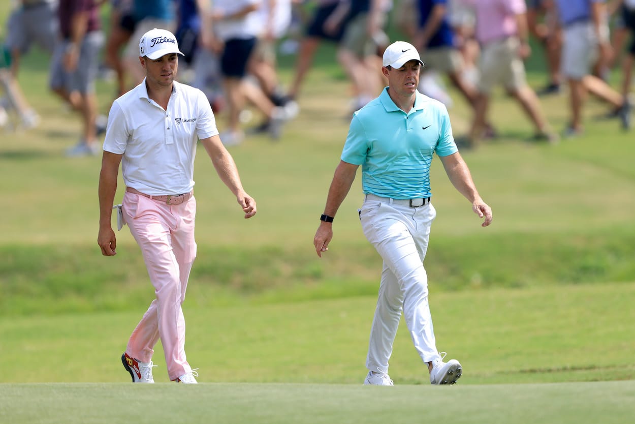 Justin Thomas and Rory McIlroy walk down the fairway.