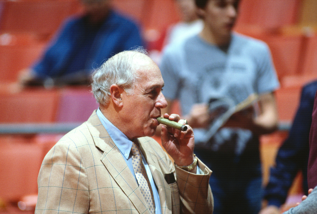 General Manager Red Auerbach of the Boston Celtics smokes a cigar behind the bench.