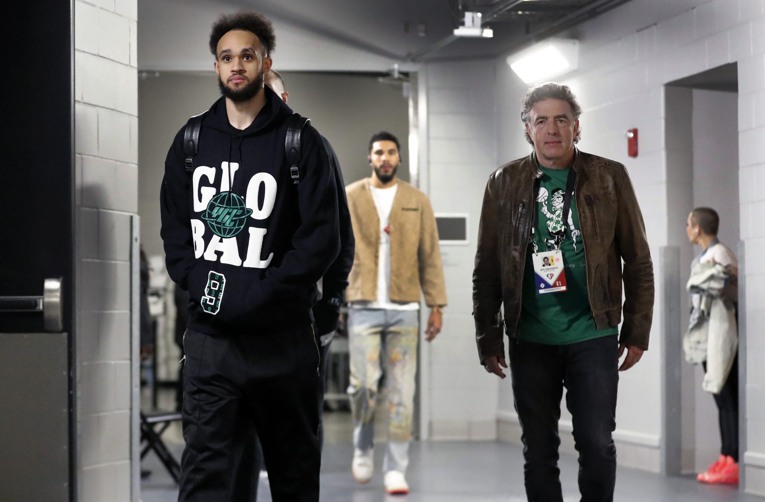 The Celtics Derrick White (left), team owner Wyc Grousbeck (right) and Jayson Tatum (background center) are pictured walking down the hall to the visitor's locker room in Milwaukee.