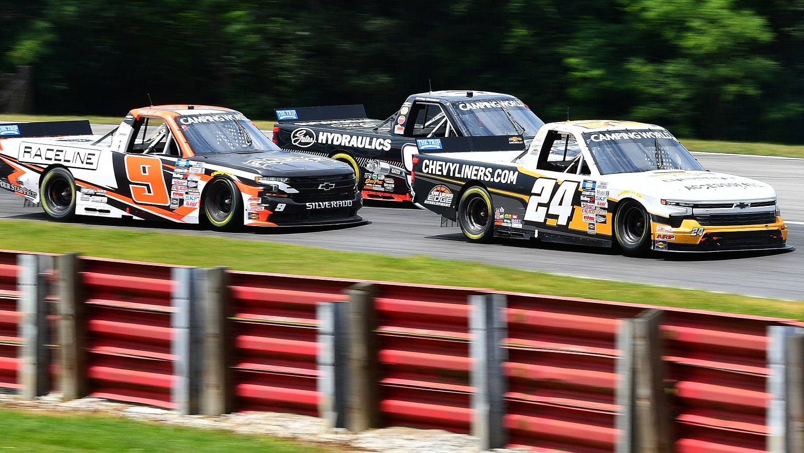 Jack Wood, driver of the No. 24 Chevrolet, and Blaine Perkins, driver of the No. 9 Chevrolet, race during the NASCAR Camping World Truck Series O'Reilly Auto Parts 150 at Mid-Ohio Sports Car Course on July 9, 2022.