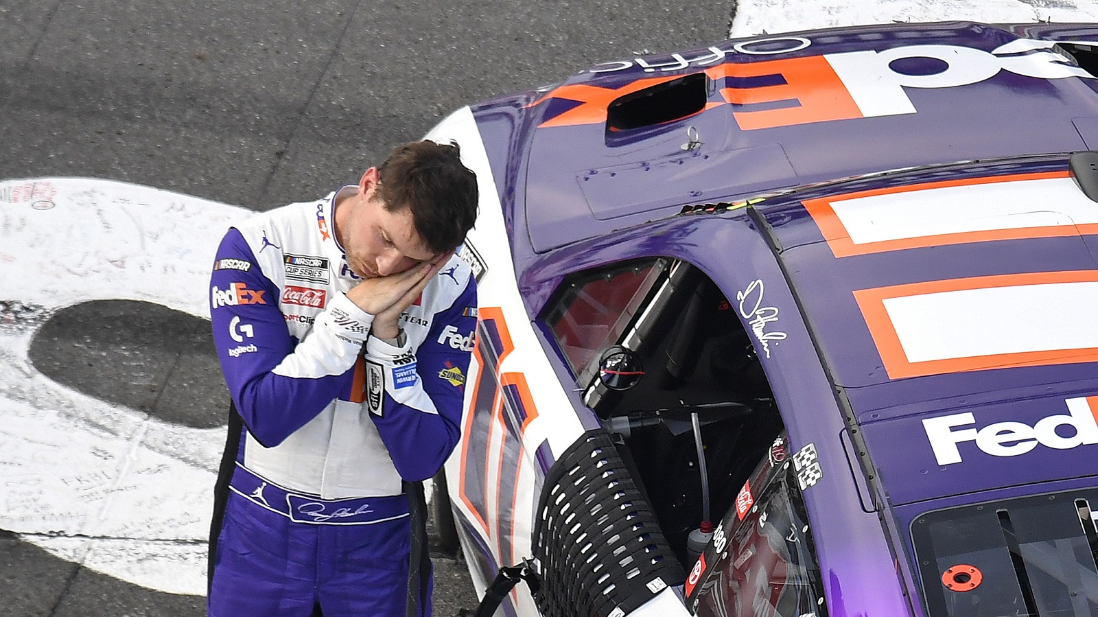 Denny Hamlin pretends to catch some nap time after winning the NASCAR Cup Series M&M's Fan Appreciation 400 at Pocono Raceway on July 24, 2022.