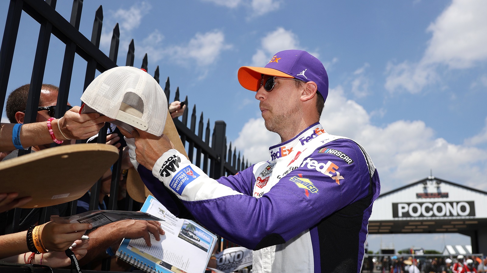 Denny Hamlin signs autographs prior to the NASCAR Cup Series M&M's Fan Appreciation 400 at Pocono Raceway on July 24, 2022.