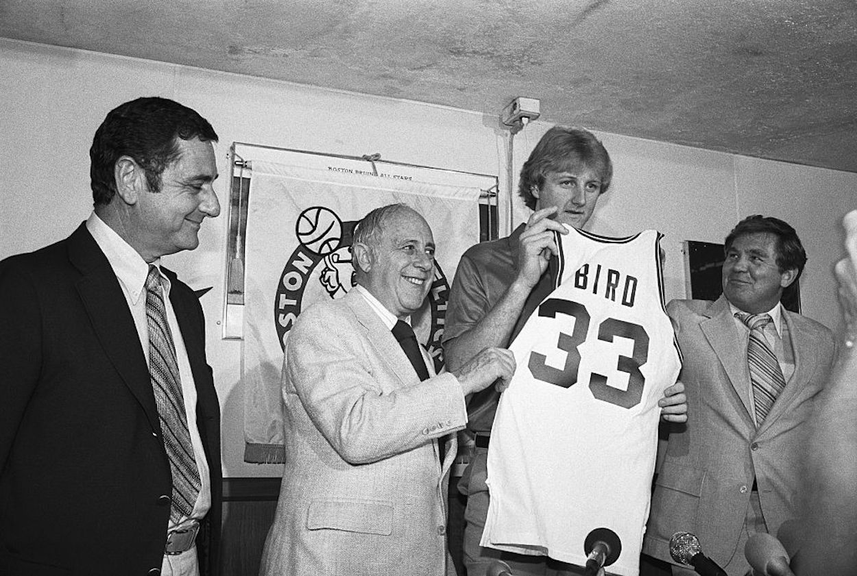 Larry Bird (C) poses after signing his Boston Celtics contract.