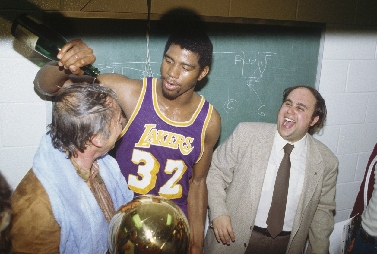 Magic Johnson of the Los Angeles Lakers pours a bottle of champagne over the owner of the Lakers Jerry Buss.