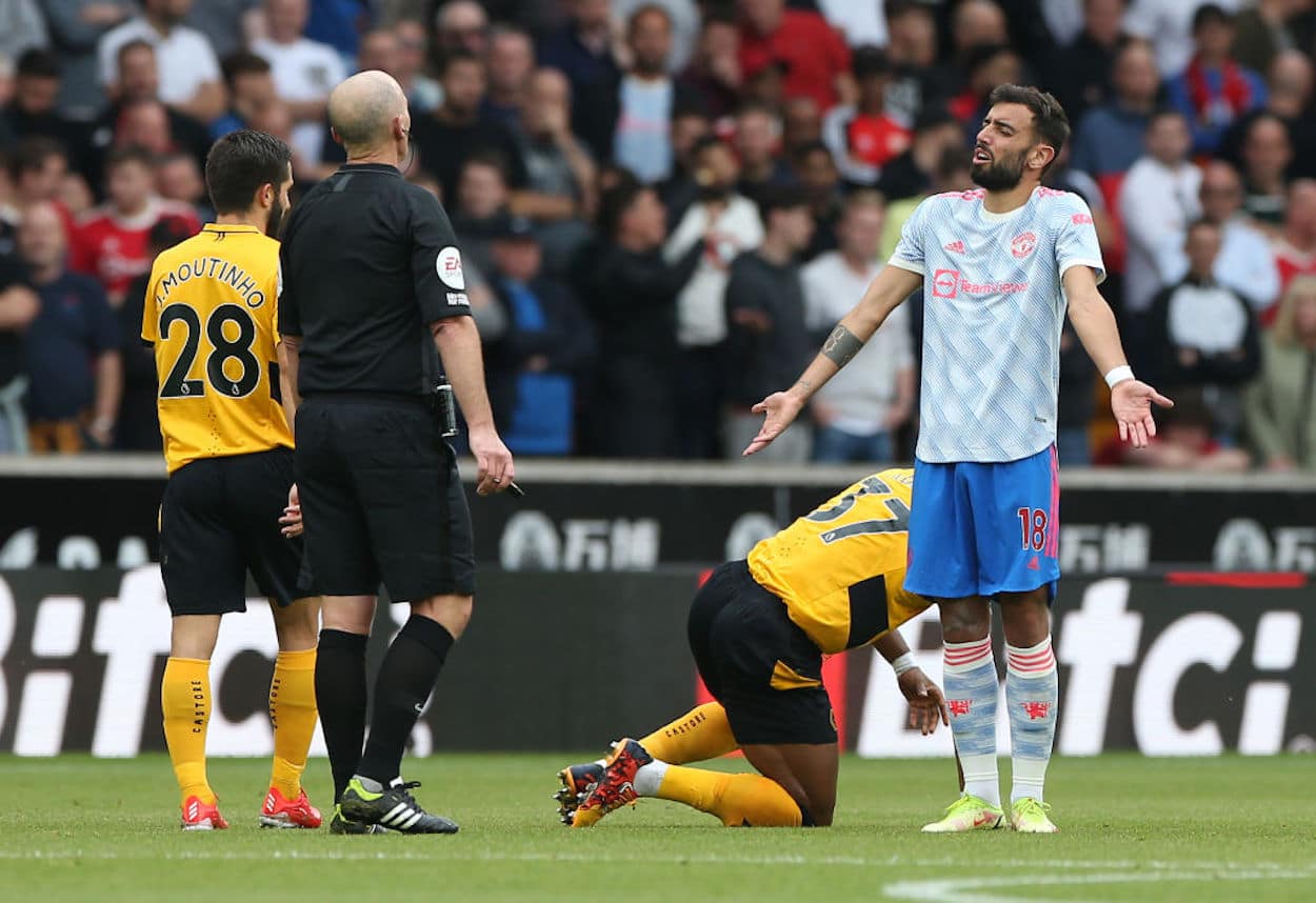 Manchester United Midfielder Bruno Fernandes (R) speaks with referee Mike Dean (R).