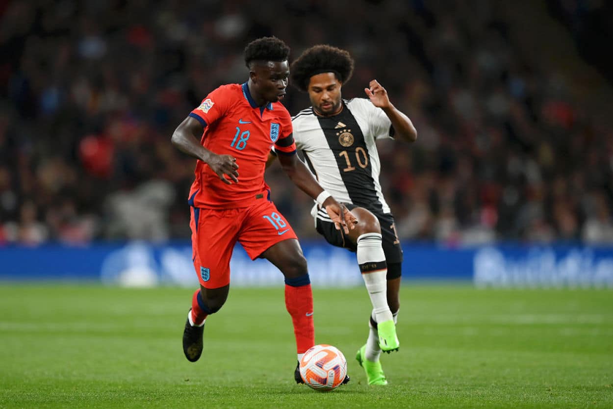 Bukayo Saka (L) dribbles past Serge Gnabry (R).