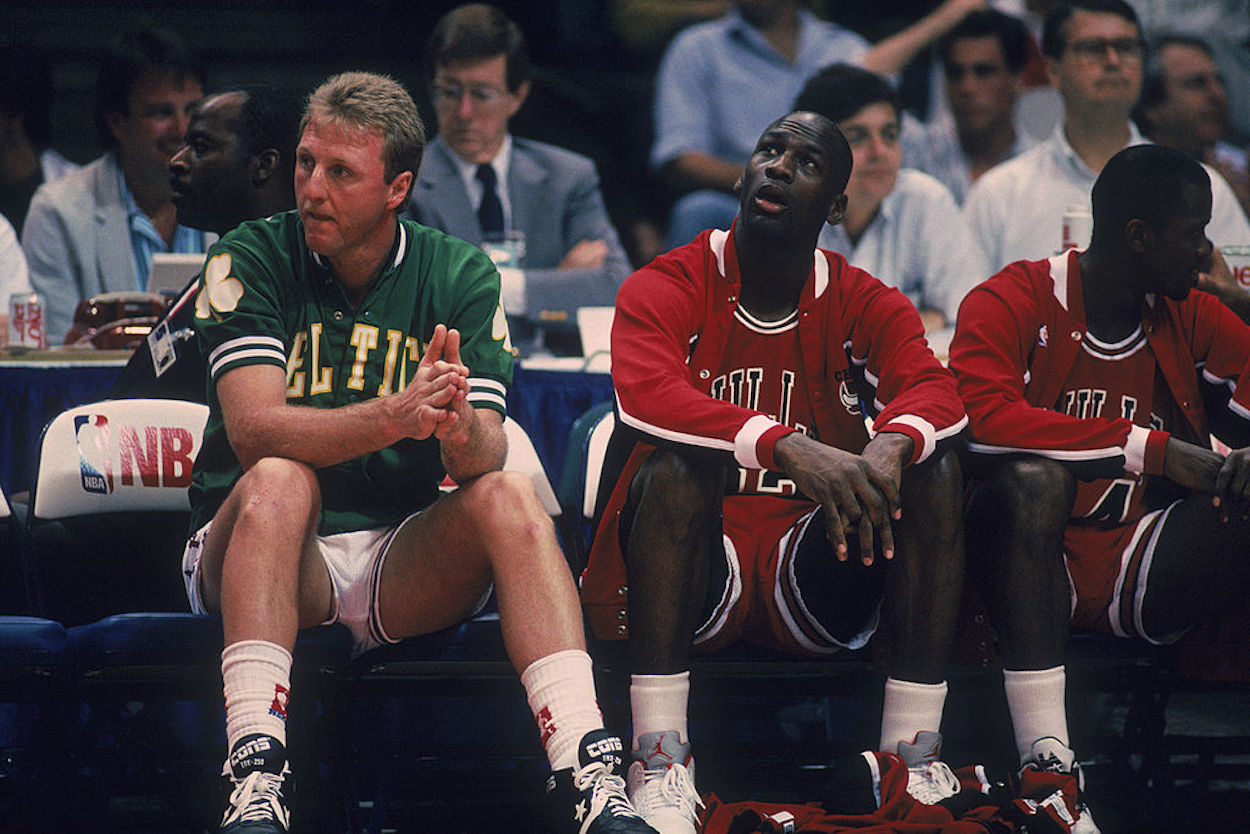 Larry Bird (L) and Michael Jordan (R) sit together on the bench.