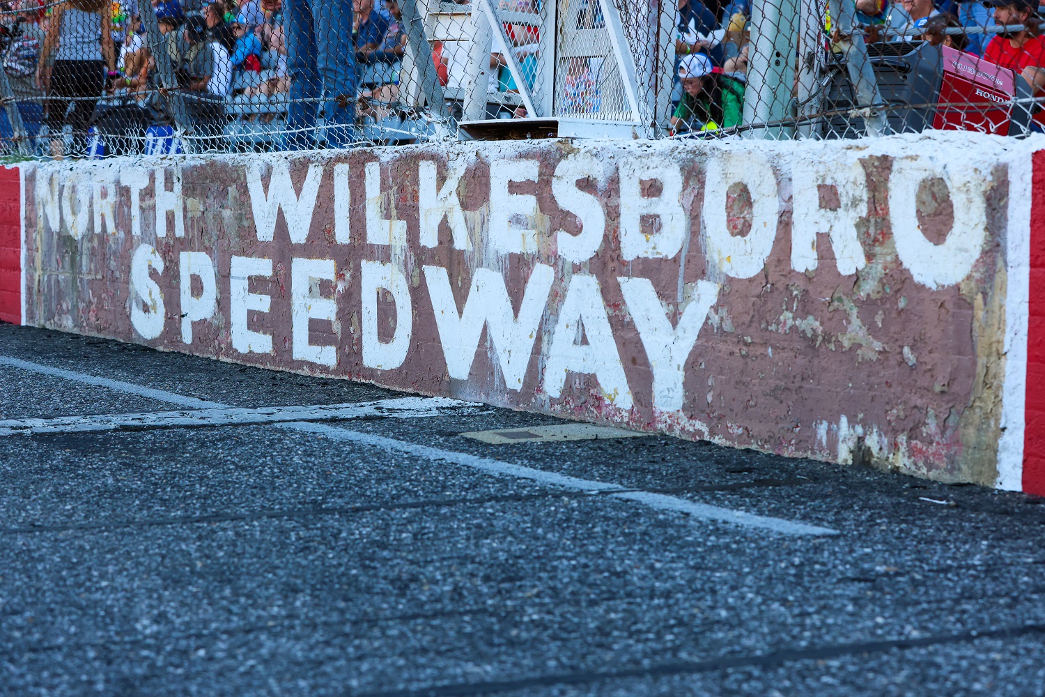 A rusted North Wilkesboro Speedway logo sits on the outer wall of the start/finish line during the Cars Tour LMSC 125 on Aug. 31, 2022, at the North Wilkesboro Speedway.