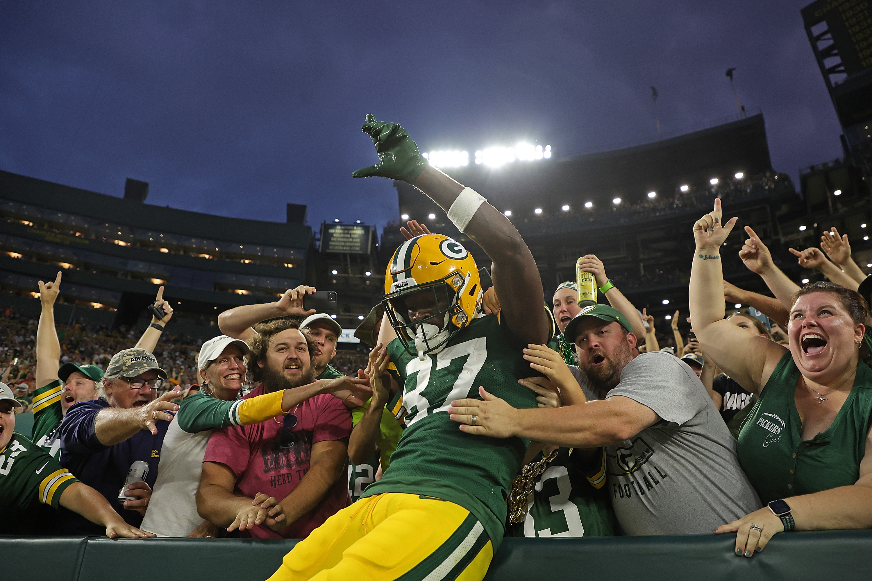 Romeo Doubs of the Green Bay Packers leaps into the stands.