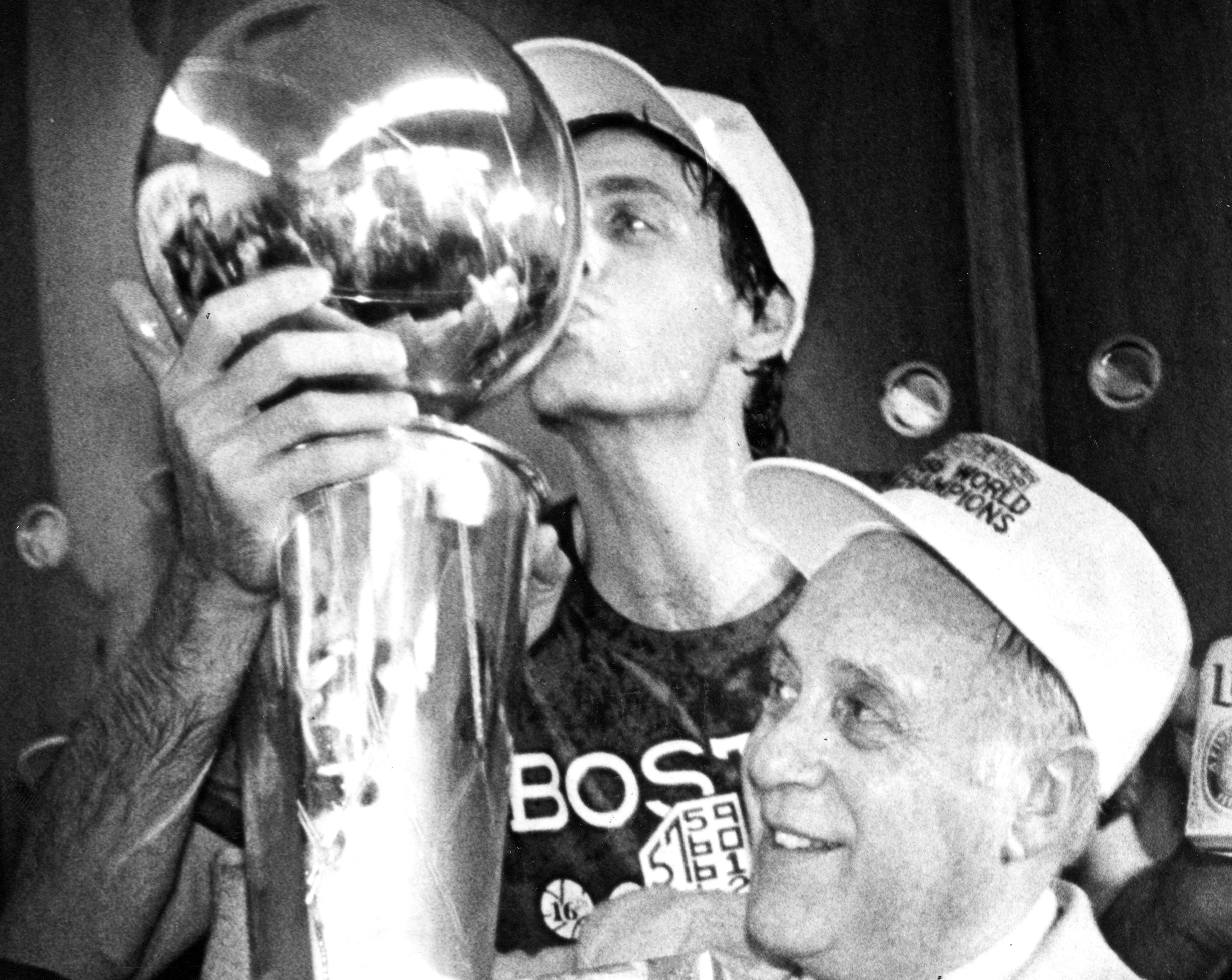 Boston Celtics' Kevin McHale kisses the championship trophy held by Celtics president Red Auerbach.