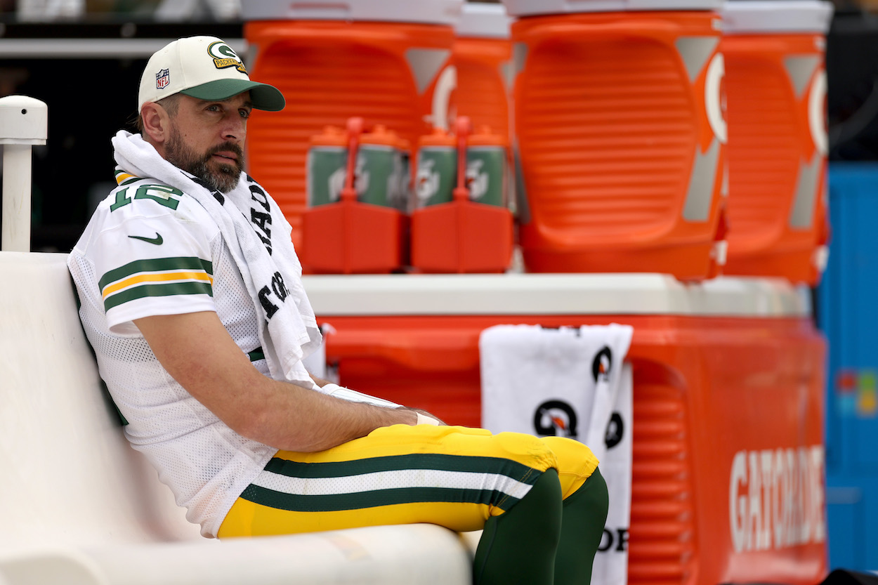 Aaron Rodgers sits on the bench during a game against the Commanders.
