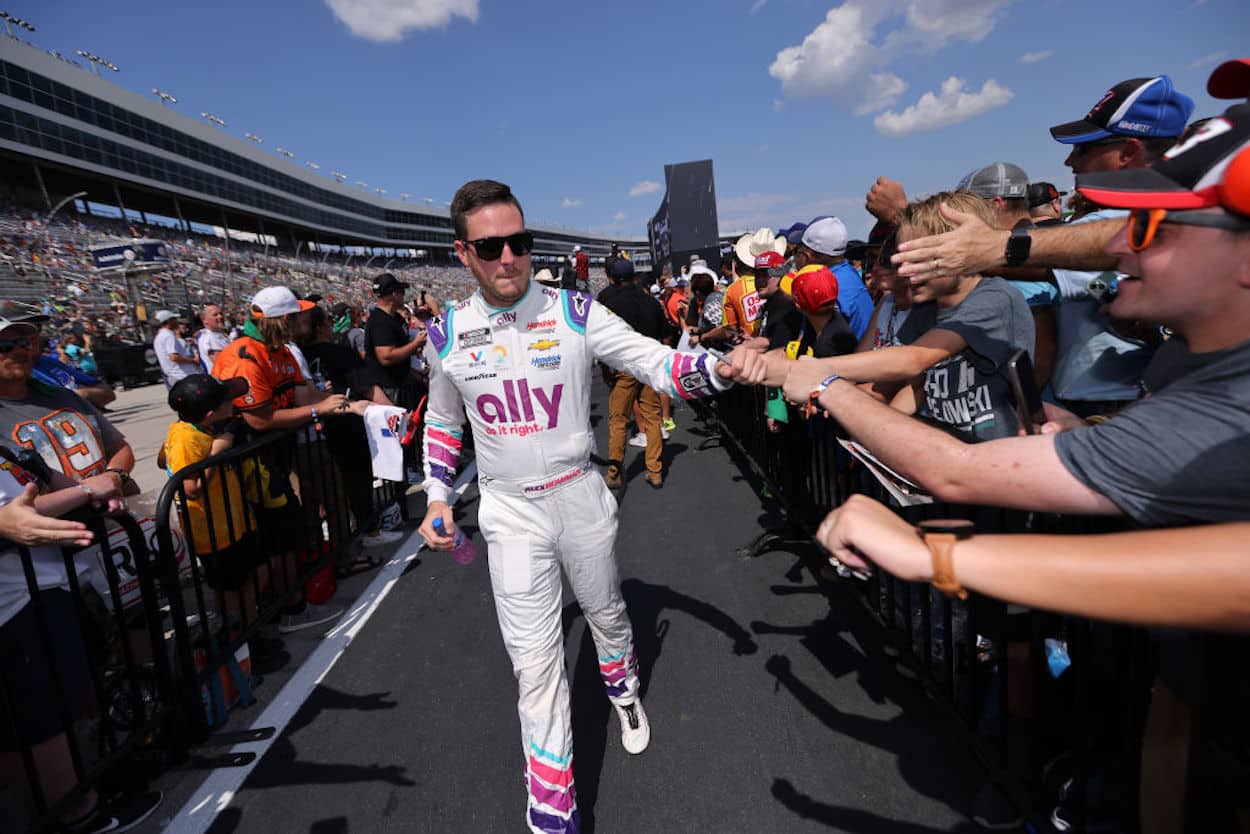 Alex Bowman high-fives fans ahead of a NASCAR Cup Series race.