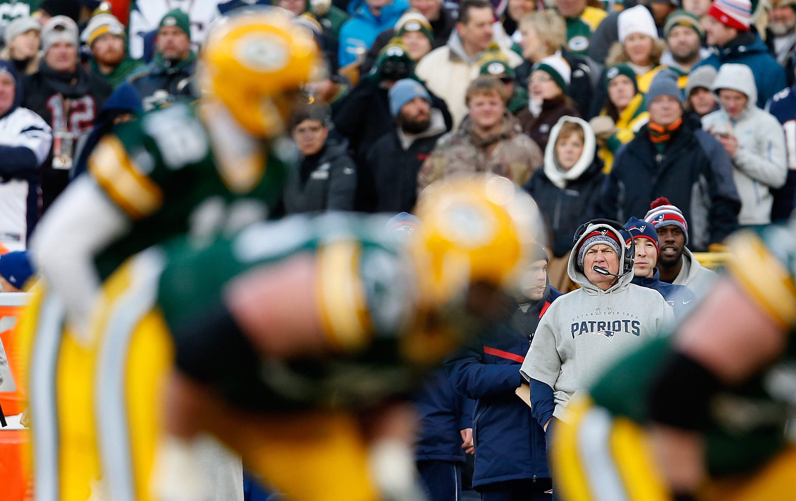 Head coach Bill Belichick of the New England Patriots looks on as quarterback Aaron Rodgers of the Green Bay Packers snaps the football.