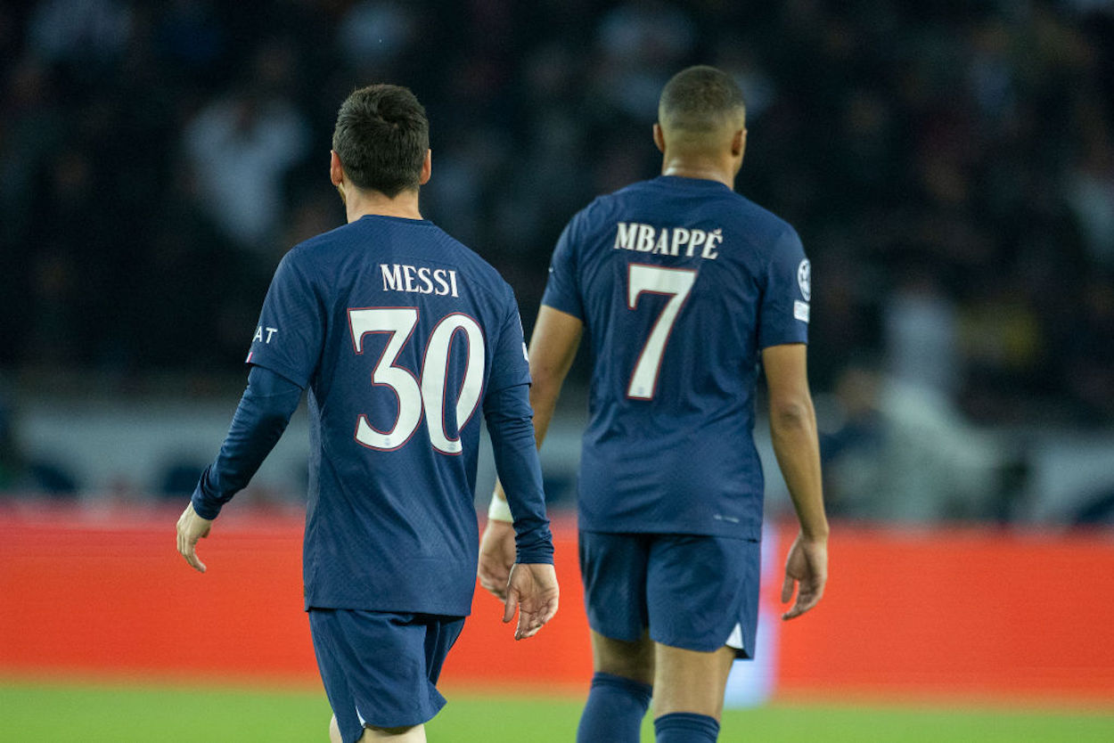 Lionel Messi (L) and Kylian Mbappe (R) stand together during a Champions League match.