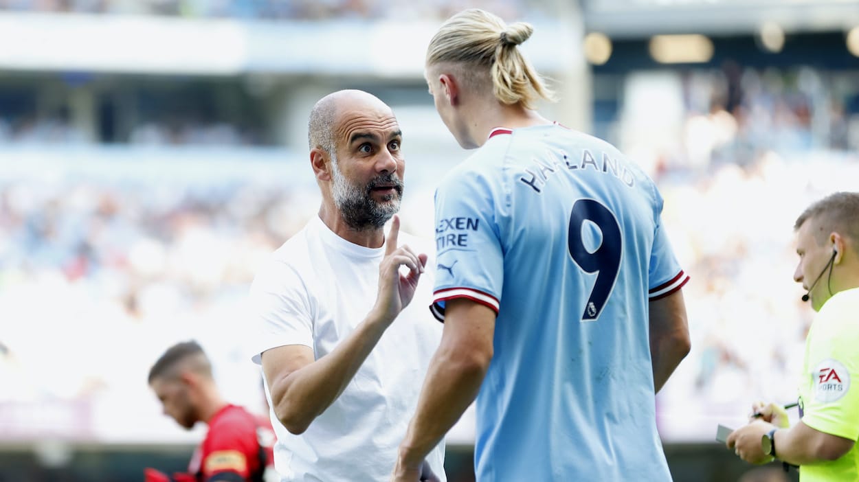 Pep Guardiola, Manager of Manchester City interacts with Erling Haaland.