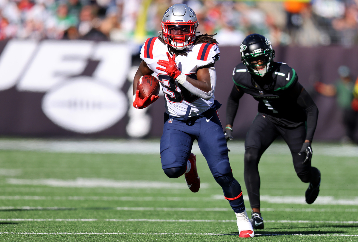 Rhamondre Stevenson 38 of the New England Patriots runs with the ball as Sauce Gardner of the New York Jets defends.