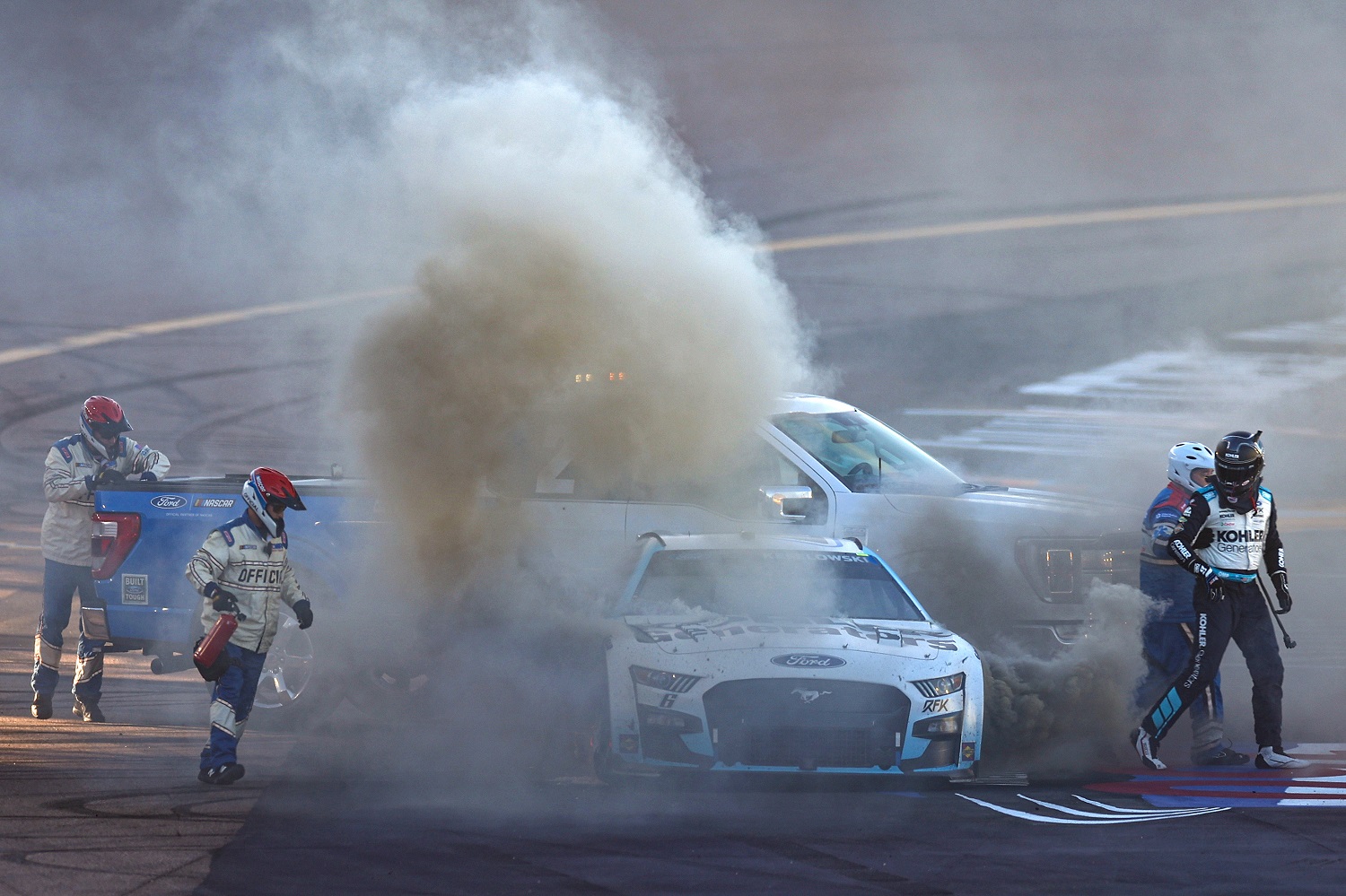 NASCAR safety crews arrive to extinguish flames from the No. 6 Ford as Brad Keselowski walks away after an on-track incident at Phoenix Raceway on Nov. 6, 2022.