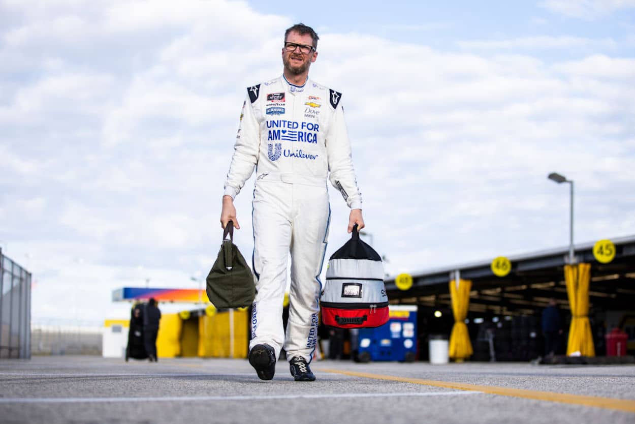 Dale Earnhardt Jr. walks through the garage area carrying his gear.