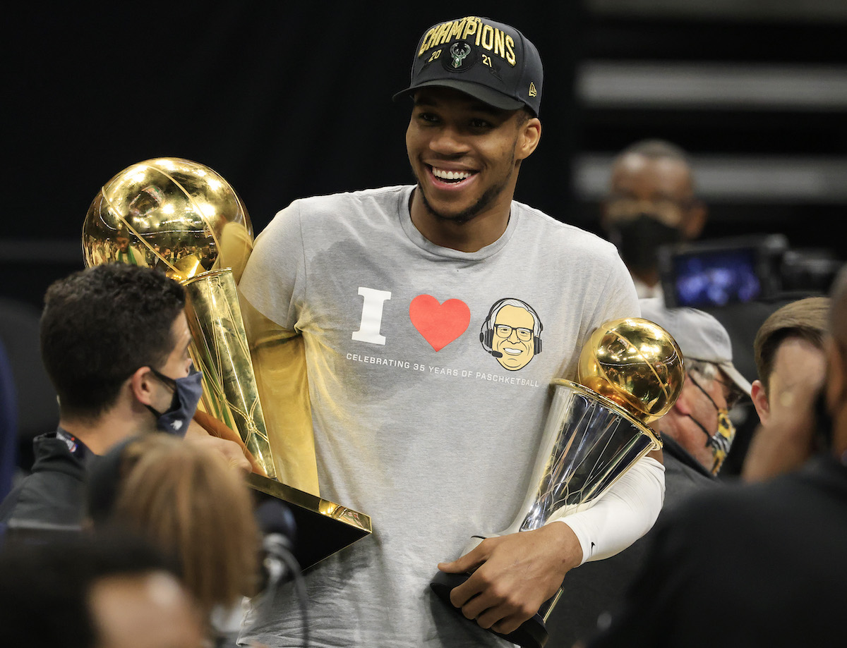Giannis Antetokounmpo of the Milwaukee Bucks holds the Bill Russell NBA Finals MVP Award and the Larry O'Brien Championship Trophy after winning the 2021 NBA Finals