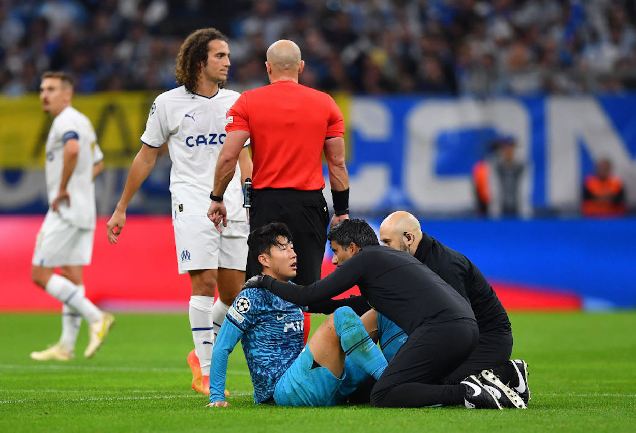 Heung-Min Son receives treatment on the pitch after suffering an injury.