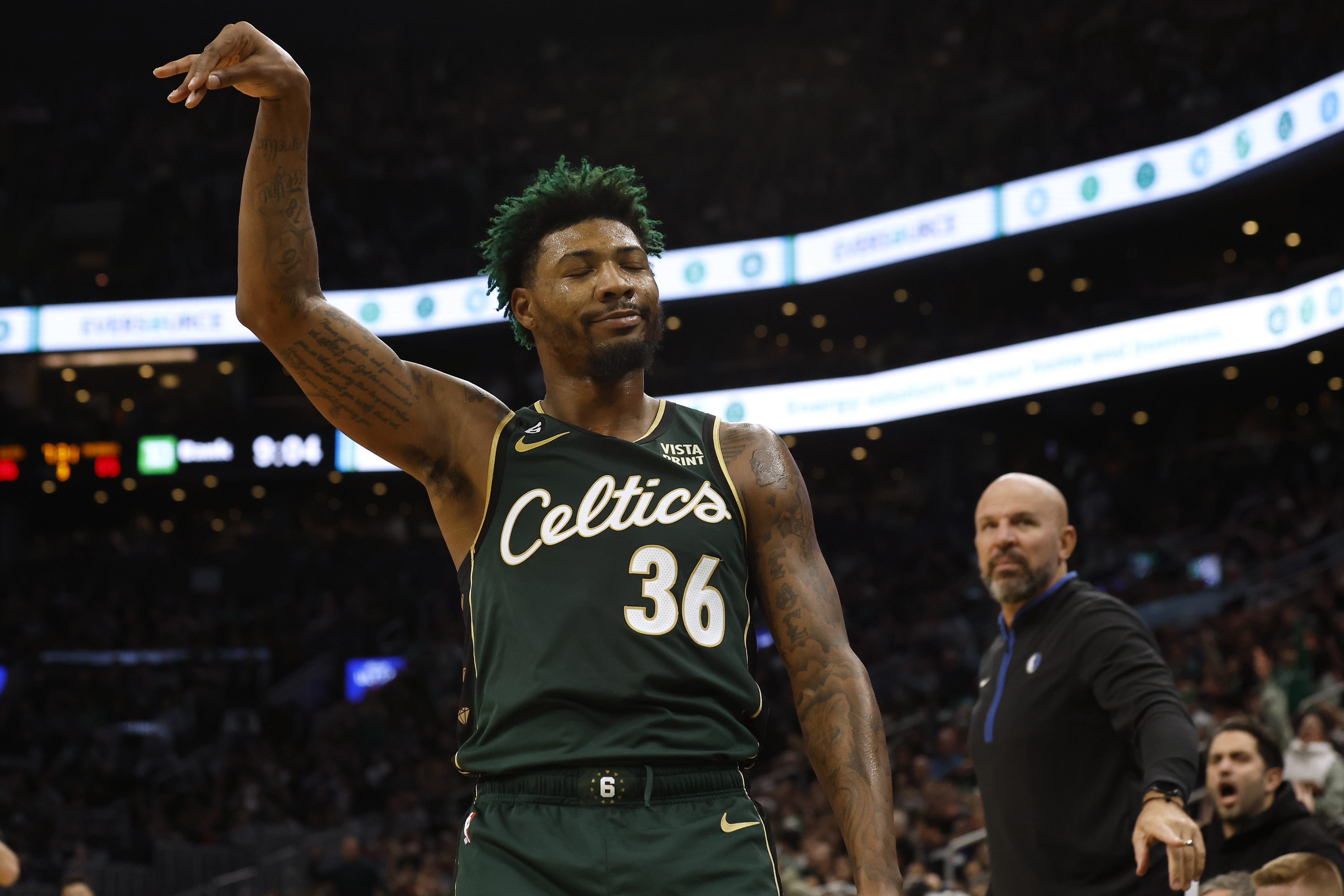 Marcus Smart of the Boston Celtics smiles at the Dallas Mavericks bench after hitting a three-point shot.