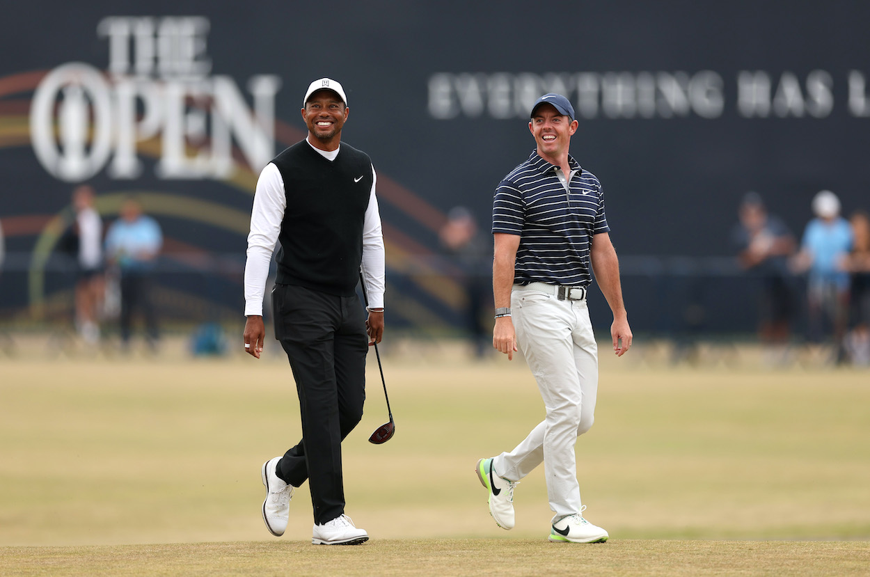 Tiger Woods and Rory McIlroy laugh as they walk up the fairway.