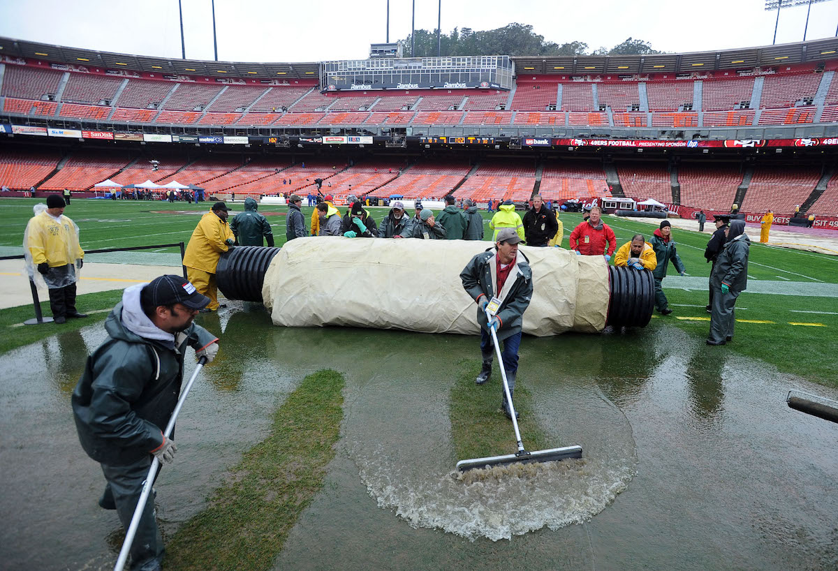 Head groundskeeper Roger Revel (C) squeegees excess water the 49ers' former stadium, Candlestick Park, in 2012