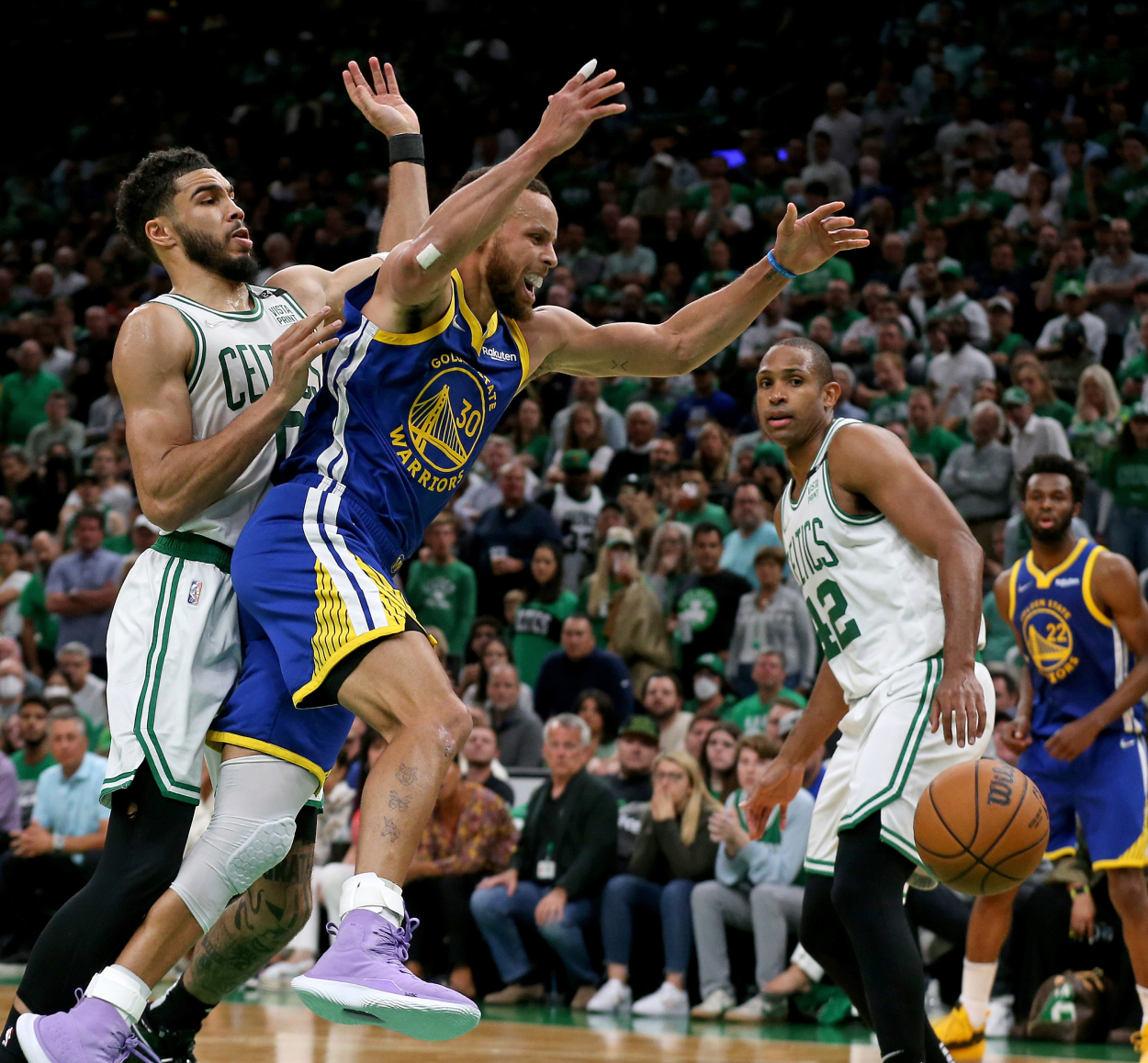 Stephen Curry of the Golden State Warriors loses the ball as Jayson Tatum and Al Horford of the Boston Celtics look on.
