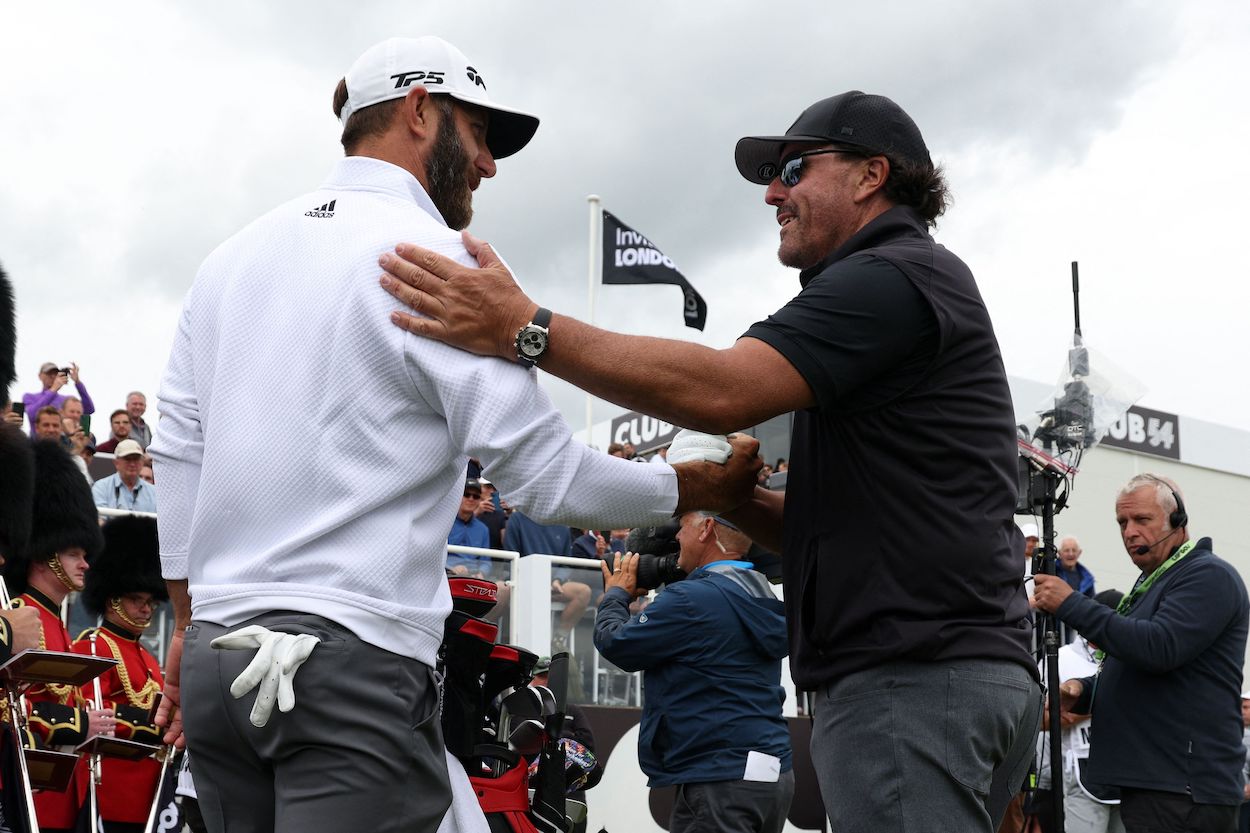 Dustin Johnson shakes hands with Phil Mickelson.