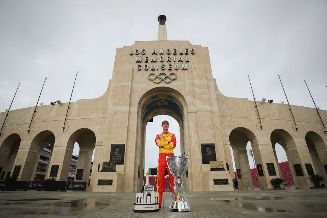 Joey Logano poses with poses with the Bill France NASCAR Cup Series Championship trophy and his NASCAR Clash at the Coliseum trophy at LA Memorial Coliseum
