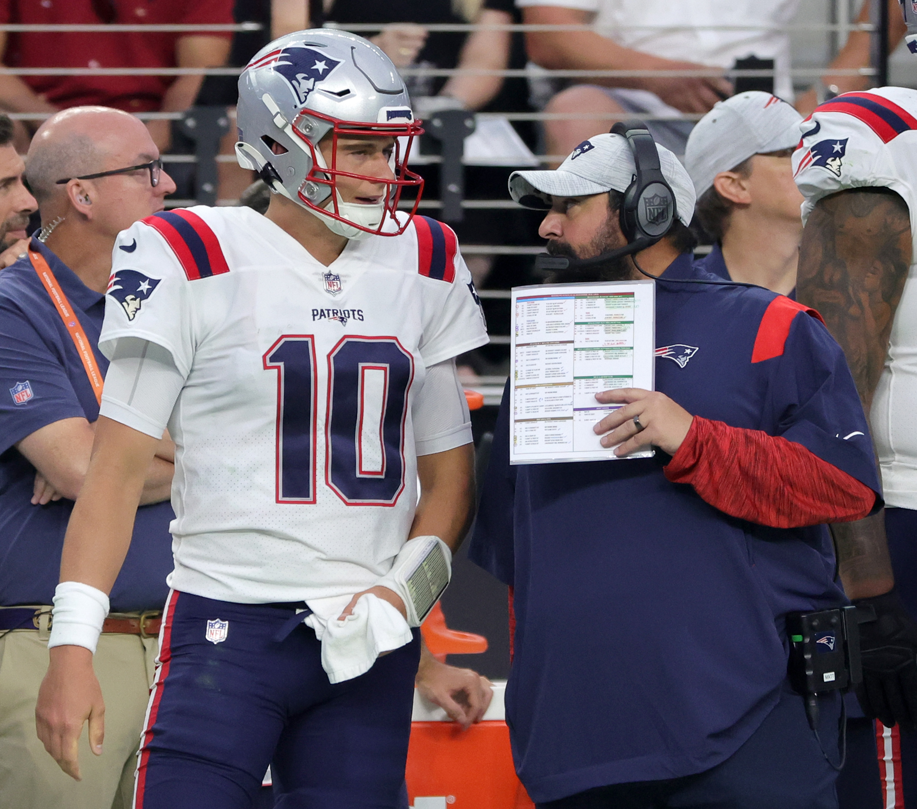 Quarterback Mac Jones and senior football advisor Matt Patricia of the New England Patriots talk on the sideline.