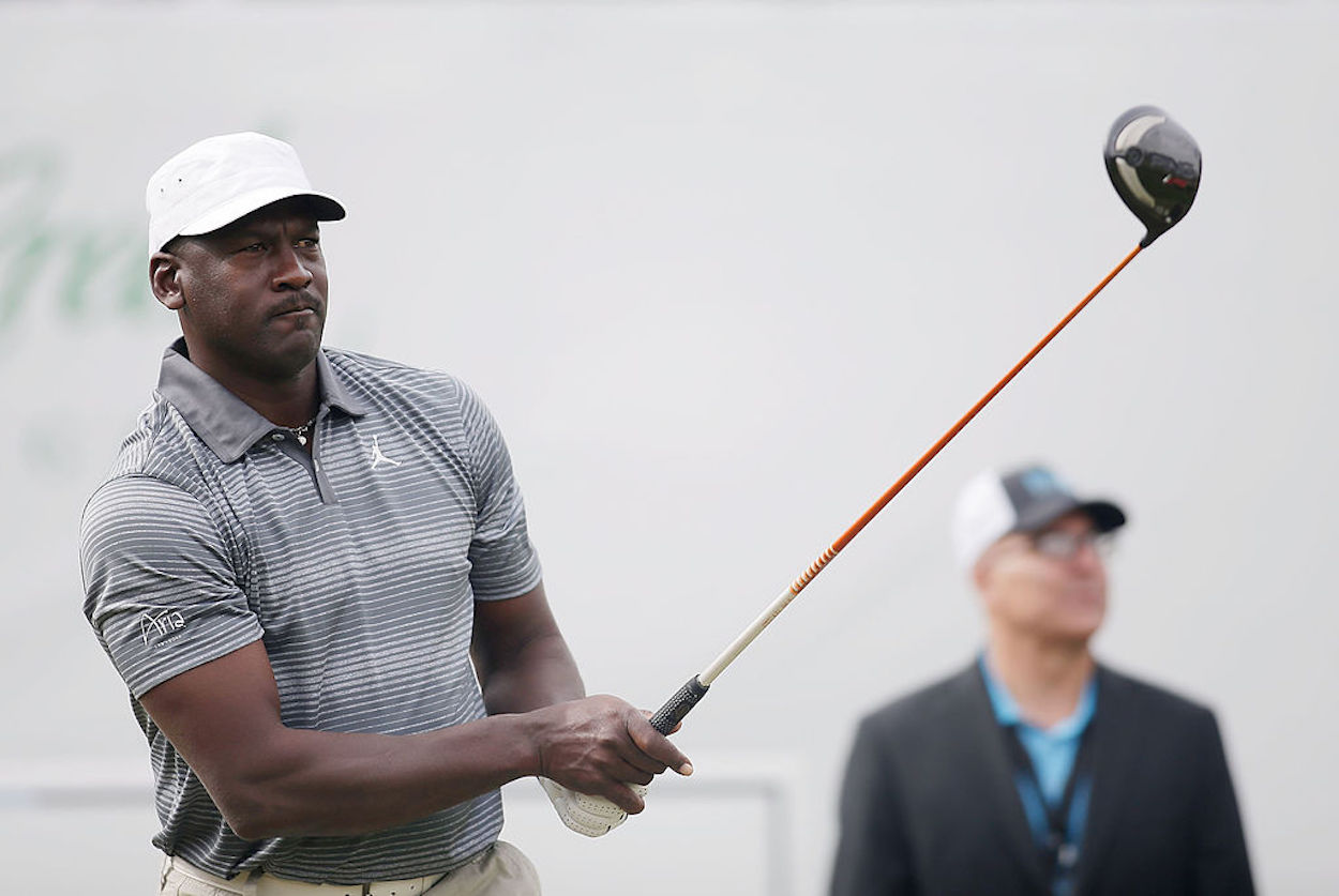 Michael Jordan looks on after completing his golf swing.