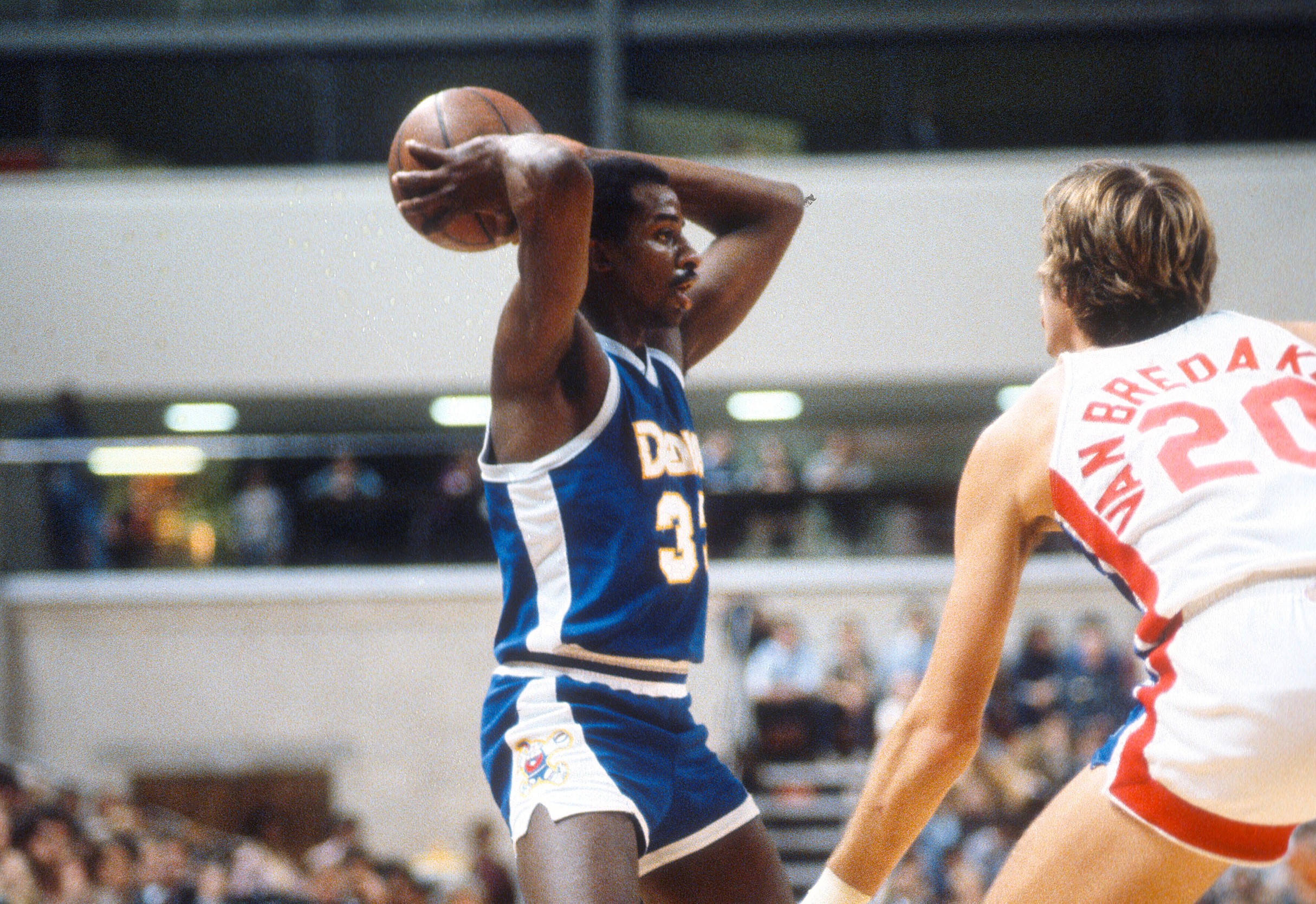 David Thompson of the Denver Nuggets looks to pass the ball over Jan van Breda Kolff of the New Jersey Nets.