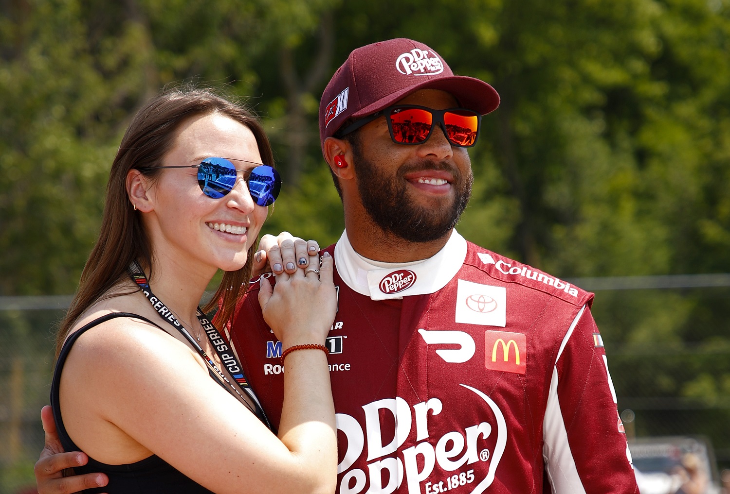 Bubba Wallace and Amanda Carter pose for photos on the grid prior to the NASCAR Cup Series Jockey Made in America 250 at Road America on July 4, 2021.