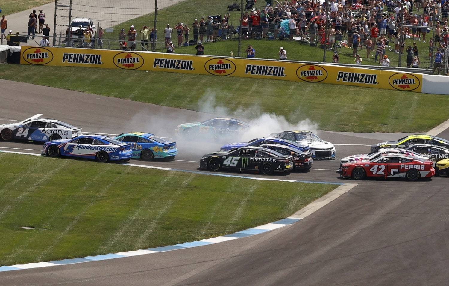 NASCAR Cup Series drivers Corey LaJoie (7) and Erik Jones (43) are involved in an incident going into Turn 1 on the first lap of the Verizon 200 at the Brickyard on July 31, 2022, at the Indianapolis Motor Speedway. | Brian Spurlock/Icon Sportswire via Getty Images