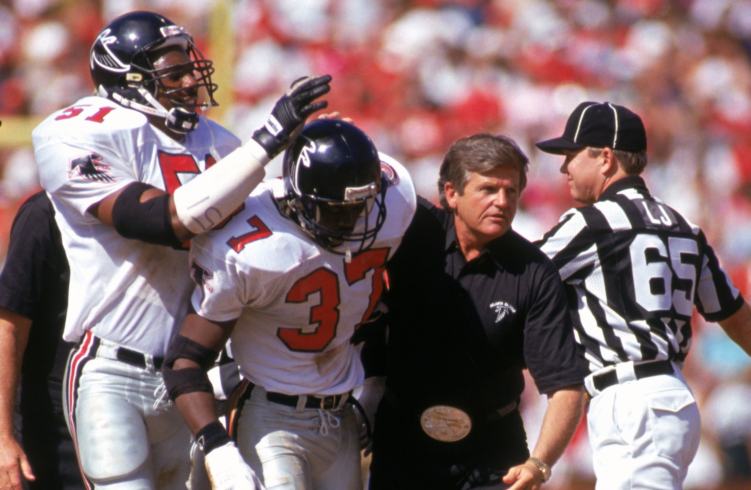 Cornerback Elbert Shelley gets help off the field from coach Jerry Glanville during a game against the San Francisco 49ers at Candlestick Park on Sept. 23, 1990.