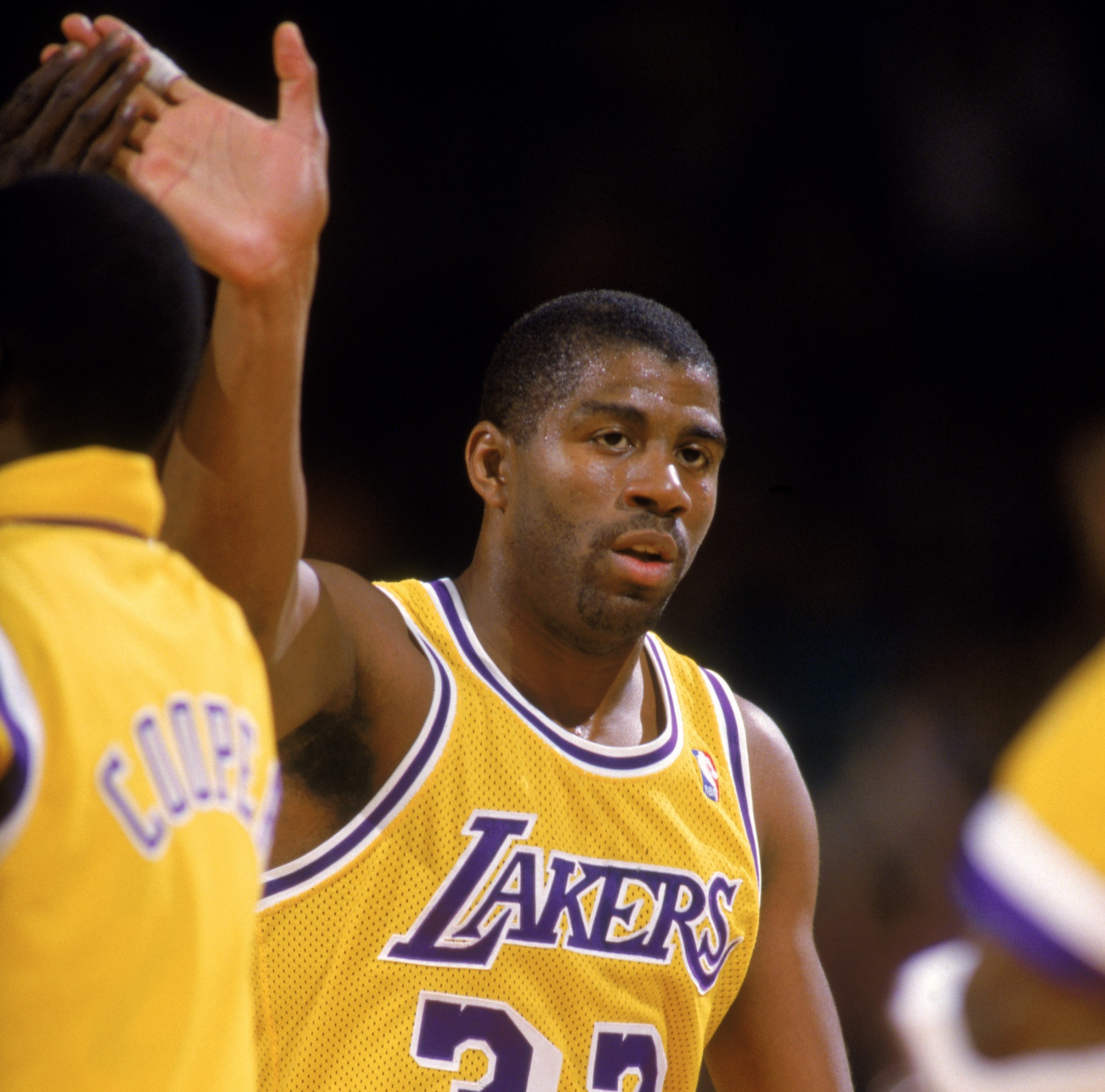Magic Johnson of the Los Angeles Lakers slaps hands with Michael Cooper.