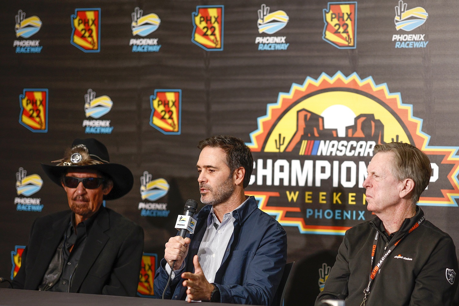 Jimmie Johnson, center, speaks to the media announcing he has taken an ownership stake in Petty GMS Motorsports as team owners Richard Petty, left, and Maury Gallagher look on.