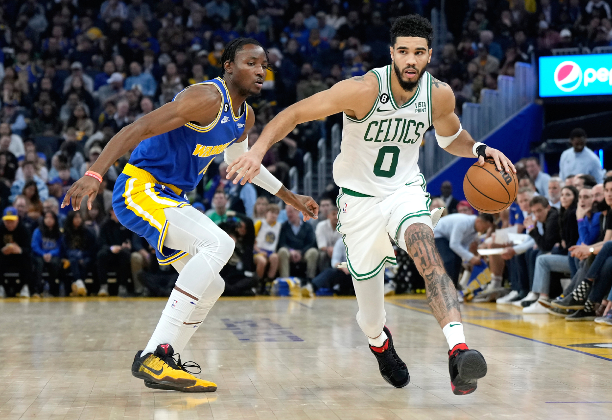 Jayson Tatum of the Boston Celtics dribbles the ball while defended by Jonathan Kuminga of the Golden State Warriors.