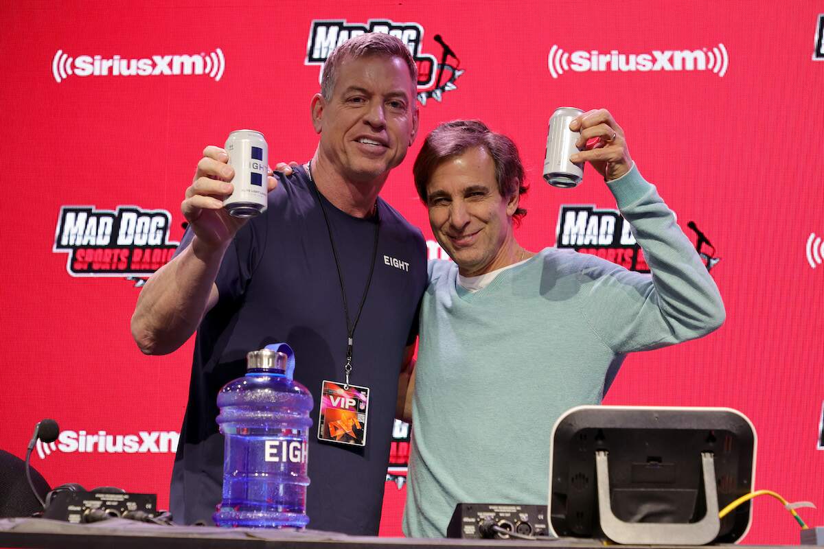 Former NFL player Troy Aikman and SiriusXM host Chris Russo hold up EIGHT Brewing Co. beer
