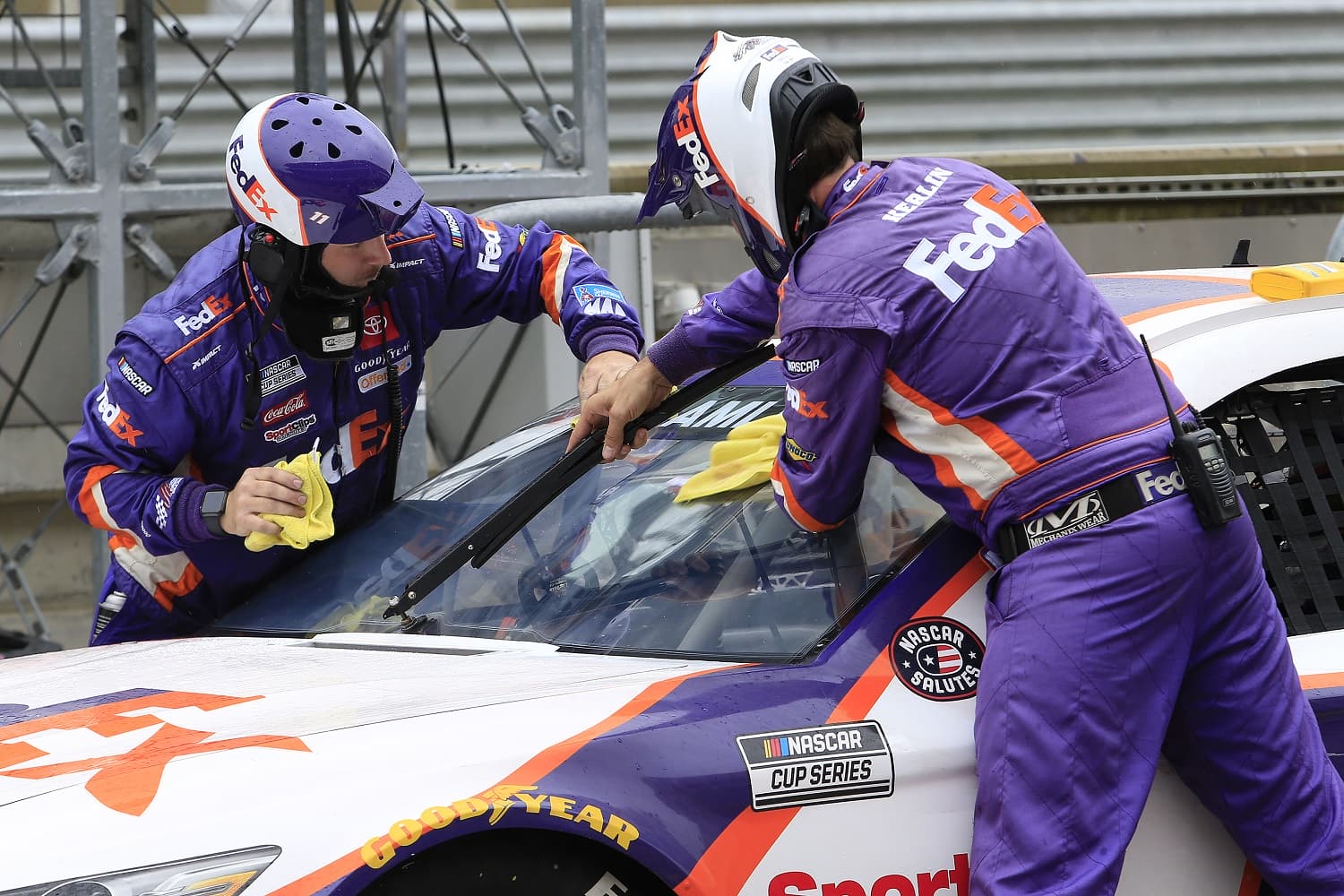 Crew members for Denny Hamlin's Toyota wipe the windshield down with RainX during the inaugural EchoPark Automotive Texas Grand Prix NASCAR Cup Series race on May 23, 2021, at Circuit of America in Austin, Texas.