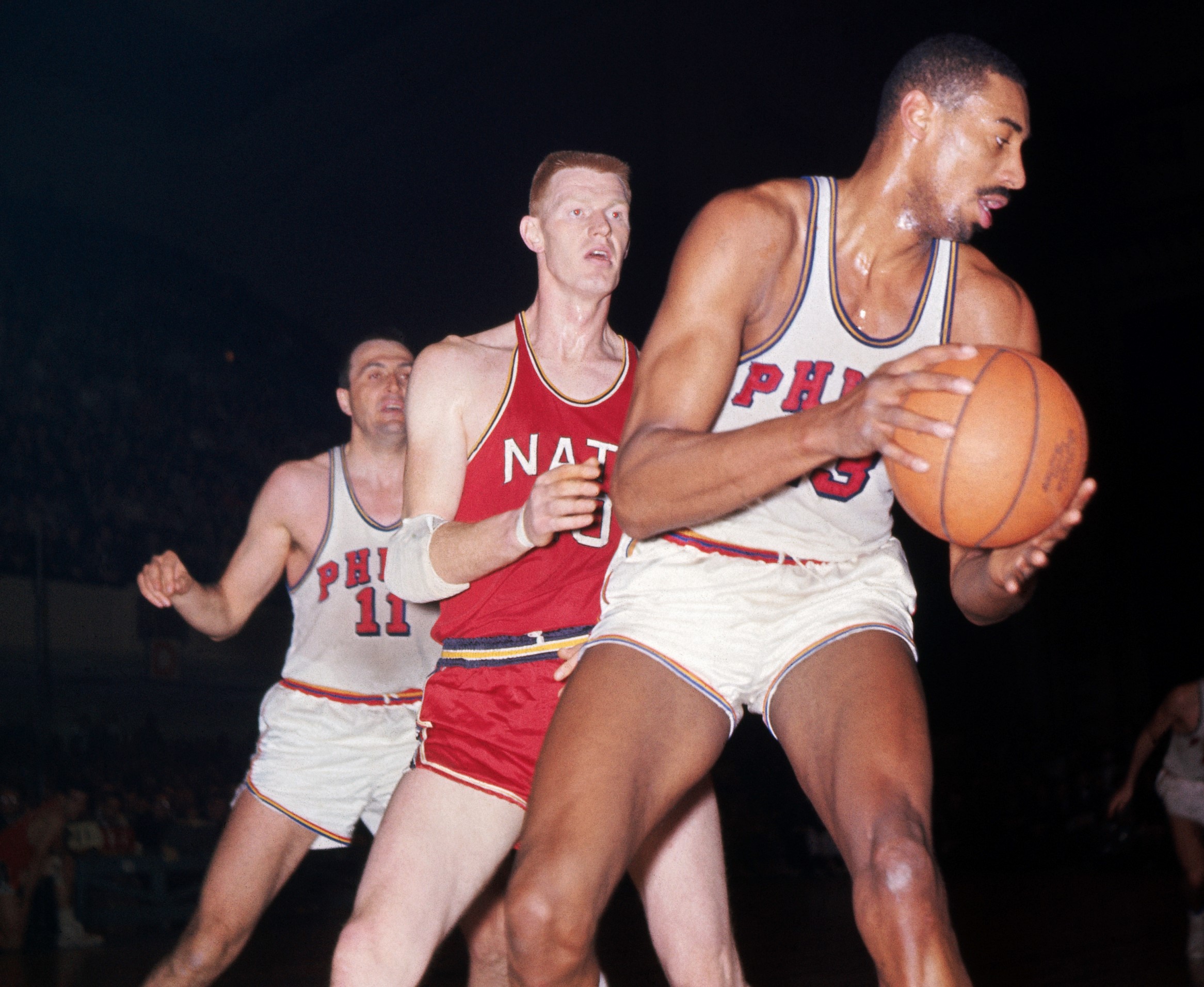 Wilt Chamberlain comes down with the rebound.
