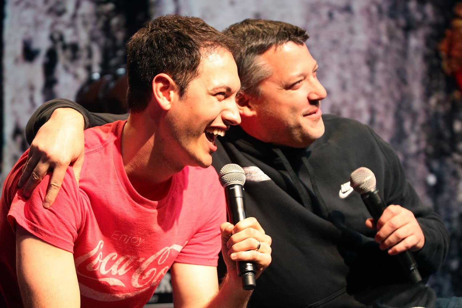 Joey Logano laughs on stage with former NASCAR driver Tony Stewart, during the Texas Motor Speedway FANDAGO event on April 6, 2017.