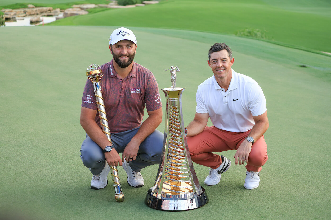 Jon Rahm and Rory McIlroy pose with trophies.