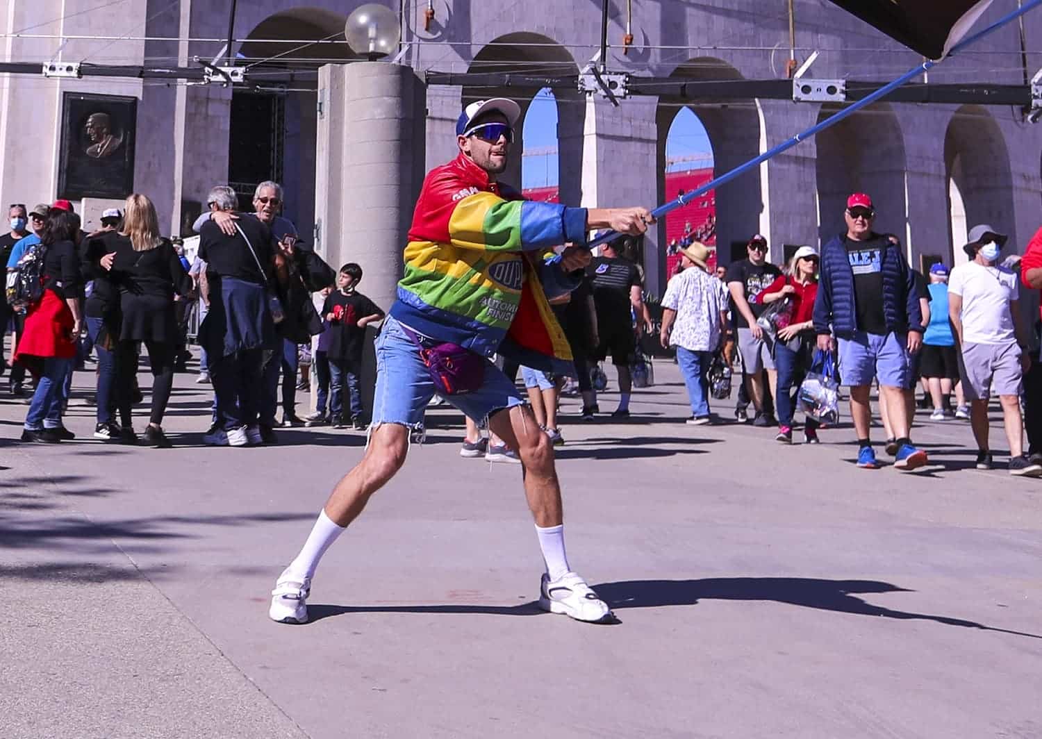 Driver Jordan Taylor, dressed in costume as alter-ego racer Rodney Sandstorm, waves a racing flag as racing fans arrive at the Busch Light Clash At The Coliseum on Feb. 6, 2022.