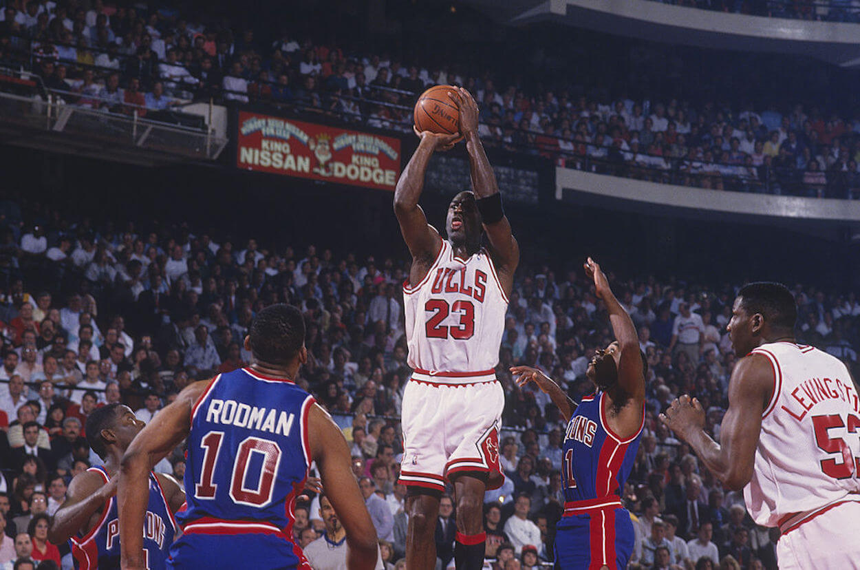Michael Jordan (C) take a jump shot over Dennis Rodman (L) and Isiah Thomas (R).