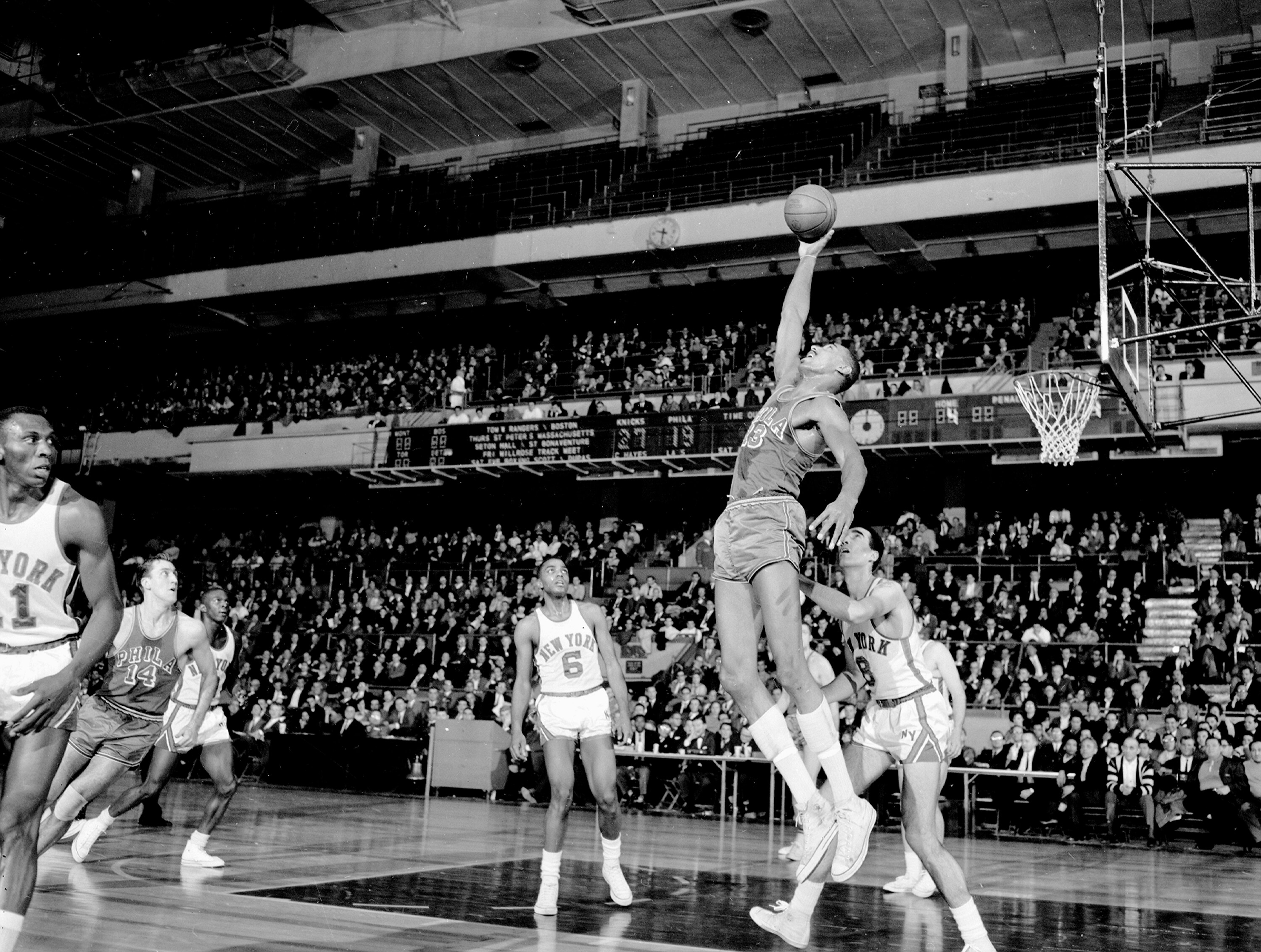 Wilt Chamberlain goes way up to pull down a rebound.